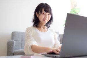 ノートパソコンとスマホを操作する女性薬剤師
